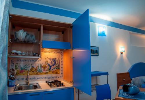 una cocina con armarios azules y fregadero en Sogni Nel Blu, en Ustica