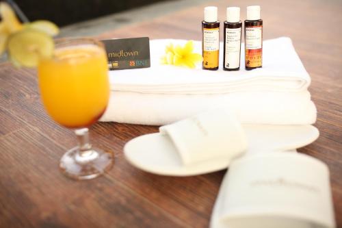a glass of orange juice next to a pile of towels at Midtown Hotel Samarinda in Samarinda