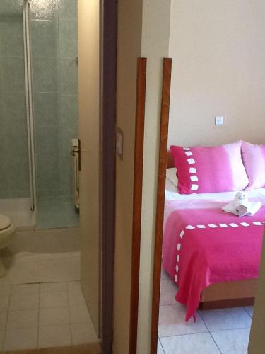 a bedroom with a pink bed and a shower at Pansion Manuela in Vrsar