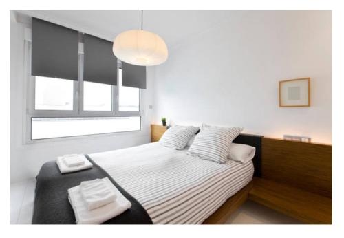 um quarto com uma cama e uma grande janela em White Cozy Flat in Donostia em San Sebastián
