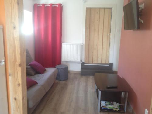 a living room with a couch and a red curtain at Gîtes Les Grandes Voies - Clé Vacances in Le Ménil