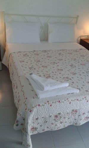 a bed with a white comforter and towels on it at Artemis Rooms in Chora Folegandros