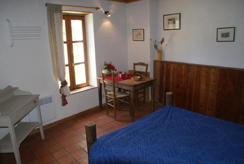 a bedroom with a bed and a table and a window at Le Berger Gourmand in Saint-Véran