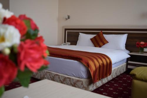 a bed in a hotel room with red flowers at Artsakh Hotel in Yerevan