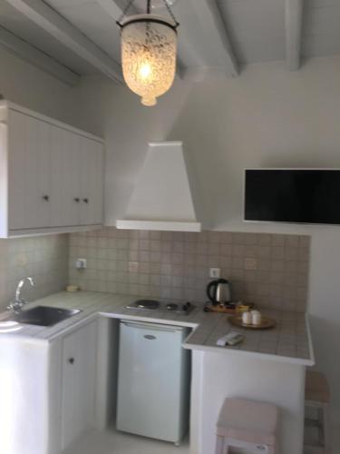 a kitchen with white cabinets and a sink and a stove at Altana Boutique Hotel in Tinos Town