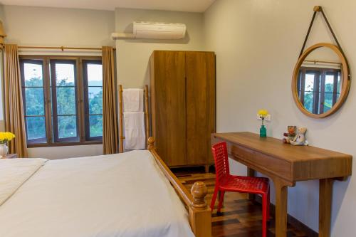 Schlafzimmer mit einem Bett, einem Schreibtisch und einem Spiegel in der Unterkunft Modern Thai Home in Ban Mae Mae