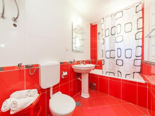 - une salle de bains rouge et blanche avec toilettes et lavabo dans l'établissement Apartments Midžor, à Petrovac na Moru