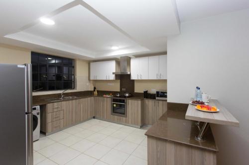 a kitchen with wooden cabinets and a stainless steel refrigerator at Cozy Residences by Trianum in Nairobi