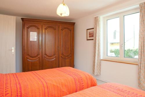 a bedroom with two beds and a wooden cabinet at Alpes et Lac in La Neuveville