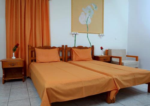 a bedroom with two beds with orange sheets and a chair at Marina Bay Aparthotel in Ratzaklíon