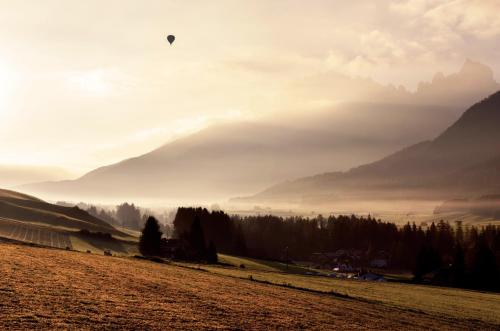a person flying a kite in a field with mountains at Hotel Rose in Villabassa