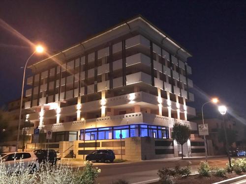 Aparthotel Capitol في غرادو: مبنى أمامه أضواء زرقاء في الليل