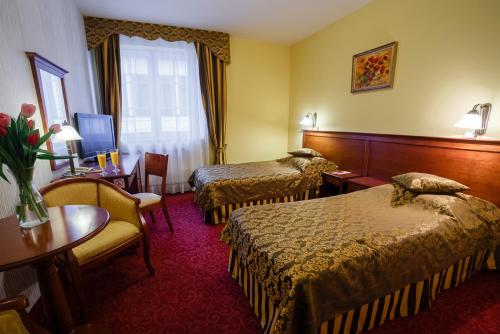 a hotel room with two beds and a table at Hotel Wellness & Spa Nowy Dwór in Rzeszów
