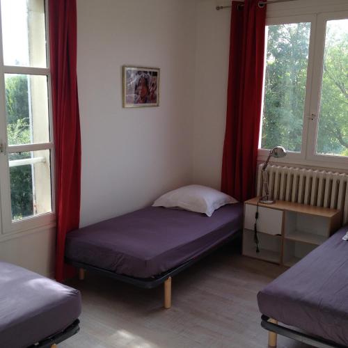 a bedroom with two beds and two windows at La grande maison de Carrouges in Carrouges