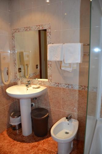 a bathroom with a sink and a toilet and a mirror at Hostal Carlos V in Puebla de Sanabria
