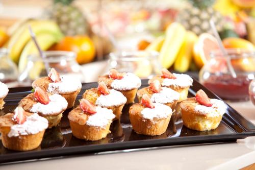 a tray of cupcakes with strawberries on top on a table at Hotel Europeo Alpine Charme & Wellness in Pinzolo