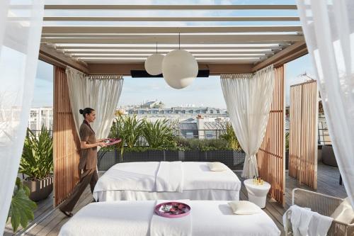 a man standing on a balcony with two beds at Mandarin Oriental, Paris in Paris