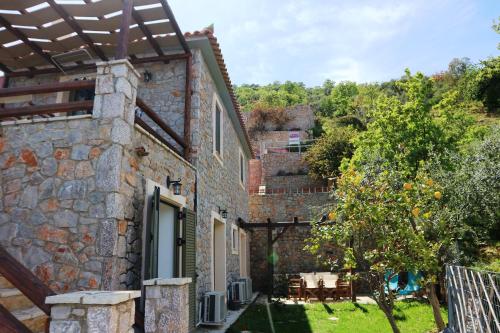 an external view of a stone house with a garden at Dio Guesthouses in Leonidion