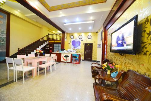 a dining room with a table and a tv on a wall at Emeishan Moon Bay Hotel in Emeishan