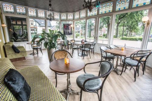 a restaurant with tables and chairs and windows at Hotel In't Holt 1654 Grand Café & Logement in Zuidhorn