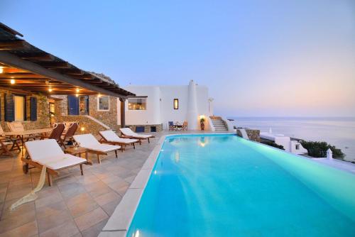 a pool in a villa with chairs and tables at Mykonian Dianthus in Elia Beach