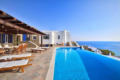 a villa with a swimming pool and the ocean at Mykonian Dianthus in Elia Beach