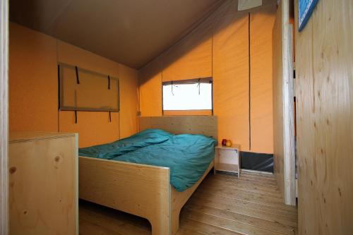 a small bedroom with a bed in the corner at Camping Marina Eemhof in Zeewolde
