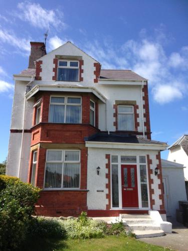 a red and white house with a red door at Witchingham B&B in Holyhead