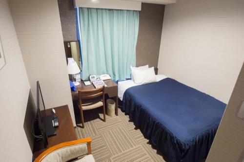 a hotel room with a bed and a desk with a telephone at Shizunai Eclipse Hotel in Shinhidaka