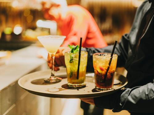 a person holding a tray with three drinks on it at Hotel Chiqui in Santander