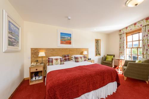 a bedroom with a large bed with a red blanket at Moorings Hotel in Fort William