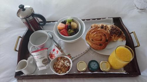 a tray of breakfast food with a plate of bread and fruit at By Appointment Suites in Johannesburg
