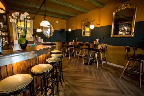 a bar with a row of stools in a restaurant at Hotel In't Holt 1654 Grand Café & Logement in Zuidhorn