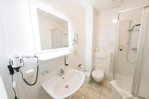 a white bathroom with a sink and a toilet at Das FRITZ Hotel in Schwerin