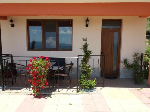 a house with a balcony with a table and flowers at Gledkata Complex in Skobelevo