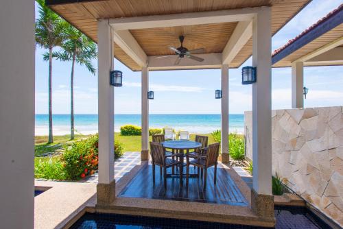 a patio with a table and chairs and the ocean at Sabah Beach Villas & Suites in Kota Kinabalu