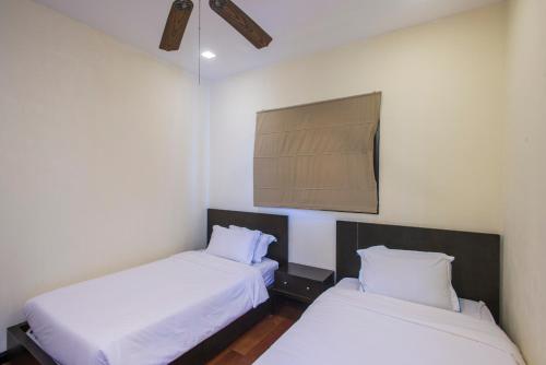 two beds in a room with white walls at Sabah Beach Villas & Suites in Kota Kinabalu