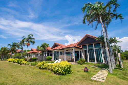 a house with palm trees in front of it at Sabah Beach Villas & Suites in Kota Kinabalu