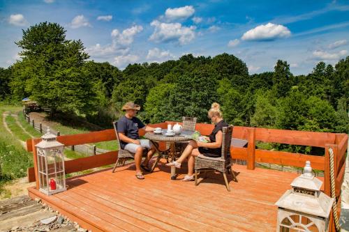 a man and two women sitting at a table on a wooden deck at Rancho Zapotoczny in Łagów