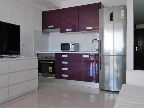 cocina con armarios morados y nevera de acero inoxidable en Apartamentos Acapulco, en Playa de las Américas