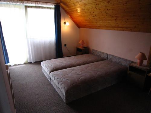 a bed in a room with a wooden ceiling at Fanni Guest House in Balatonvilágos