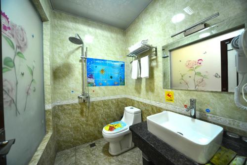 een badkamer met een wastafel, een toilet en een spiegel bij Emeishan Moon Bay Hotel in Emeishan