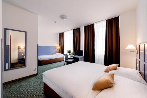 una camera d'albergo con due letti e uno specchio di Central Hotel Prague a Praga