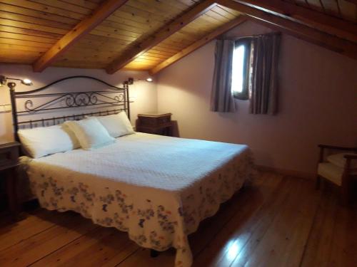 a bedroom with a bed with a white blanket and a window at Arcalís in Rascafría