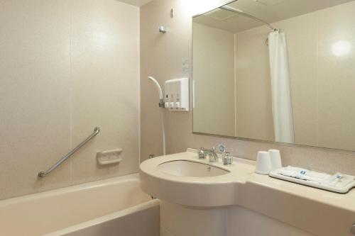 W łazience znajduje się umywalka, lustro i wanna. w obiekcie Comfort Inn Omihachiman w mieście Omihachiman
