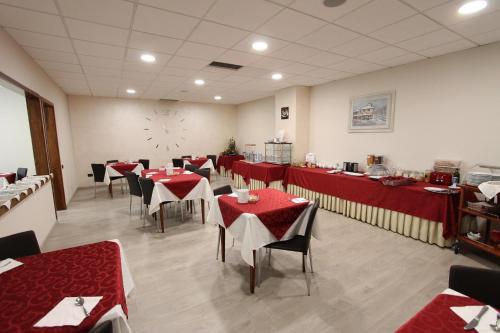un restaurante con mesas y sillas rojas y un reloj en la pared en Hotel Europa, en Biella