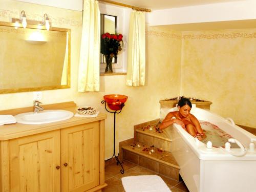 a child laying in a bath tub in a bathroom at Hotel Berghof in Neustift im Stubaital