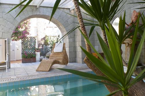 a swimming pool with wicker chairs and a palm tree at Resort Villa Flavio in Ischia