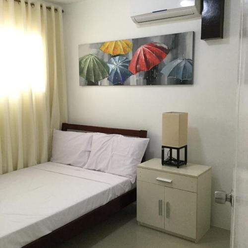 a bedroom with a bed and a painting of umbrellas at Bords Sweet Home in Davao City
