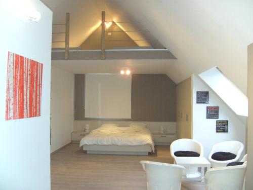 a bedroom with a bed and two white chairs at 't Vossenerf in De Haan